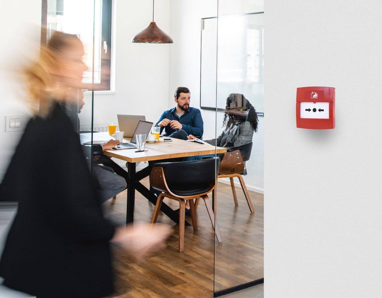 People at work in an office, with a call point unit installed on a wall